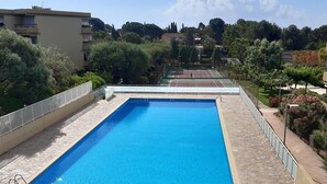 A rectangular swimming pool with a clear blue water surface, surrounded by a stone deck and metal railings. - Apartment with parking, air conditioning - 4 guests (Bormes-les-Mimosas)