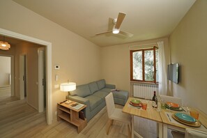 A compact living space with a sofa, dining table, and a ceiling fan. - Olive Garden Garda - pool & view Gardagate (Moniga del Garda)