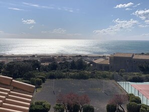 A coastal view with buildings, a parking area, and a tennis court. - Apartment sea view, parking - 6 guests (Fleury-Saint-Pierre-la-Mer)