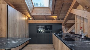 Eine moderne Küche mit Holzbalken, einem Oberlicht und einer schwarzen Arbeitsplatte.