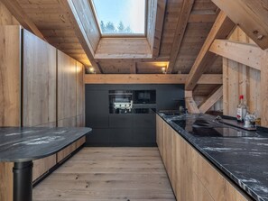 Eine moderne Küche mit Holzbalken, einem Oberlicht und einer schwarzen Arbeitsplatte.