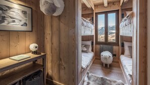 Ein gemütliches Blockhäuschen im Inneren mit Holzwänden, einem Etagenbett, einem Schreibtisch mit Lampe und einem gerahmten Bild an der Wand.