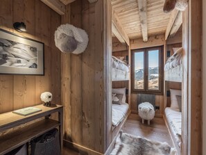 Ein gemütliches Blockhäuschen im Inneren mit Holzwänden, einem Etagenbett, einem Schreibtisch mit Lampe und einem gerahmten Bild an der Wand.