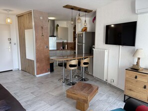 Eine moderne Küche mit Essbereich, einem an der Wand montierten Fernseher und einem Holzschrank mit Schubladen.