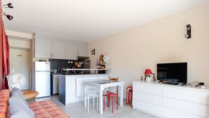 A compact living space with a kitchenette, a dining area, a sofa, and a TV. - Ground floor apartment near beach - 4 guests (Fleury-Saint-Pierre-la-Mer)