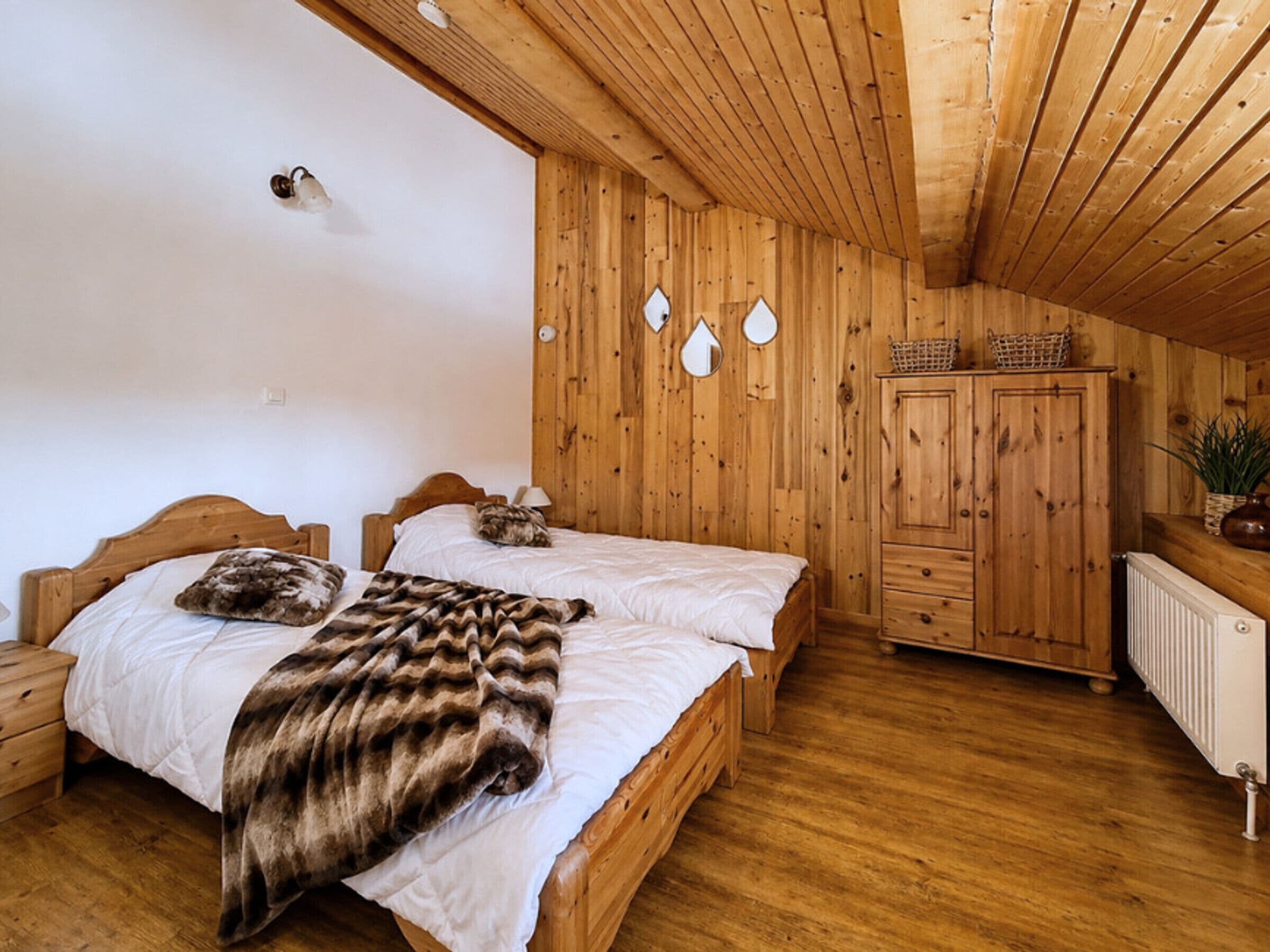 Una habitación con paneles de madera, dos camas, un armario y un radiador.
