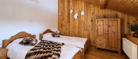 Una habitación con paneles de madera, dos camas, un armario y un radiador.