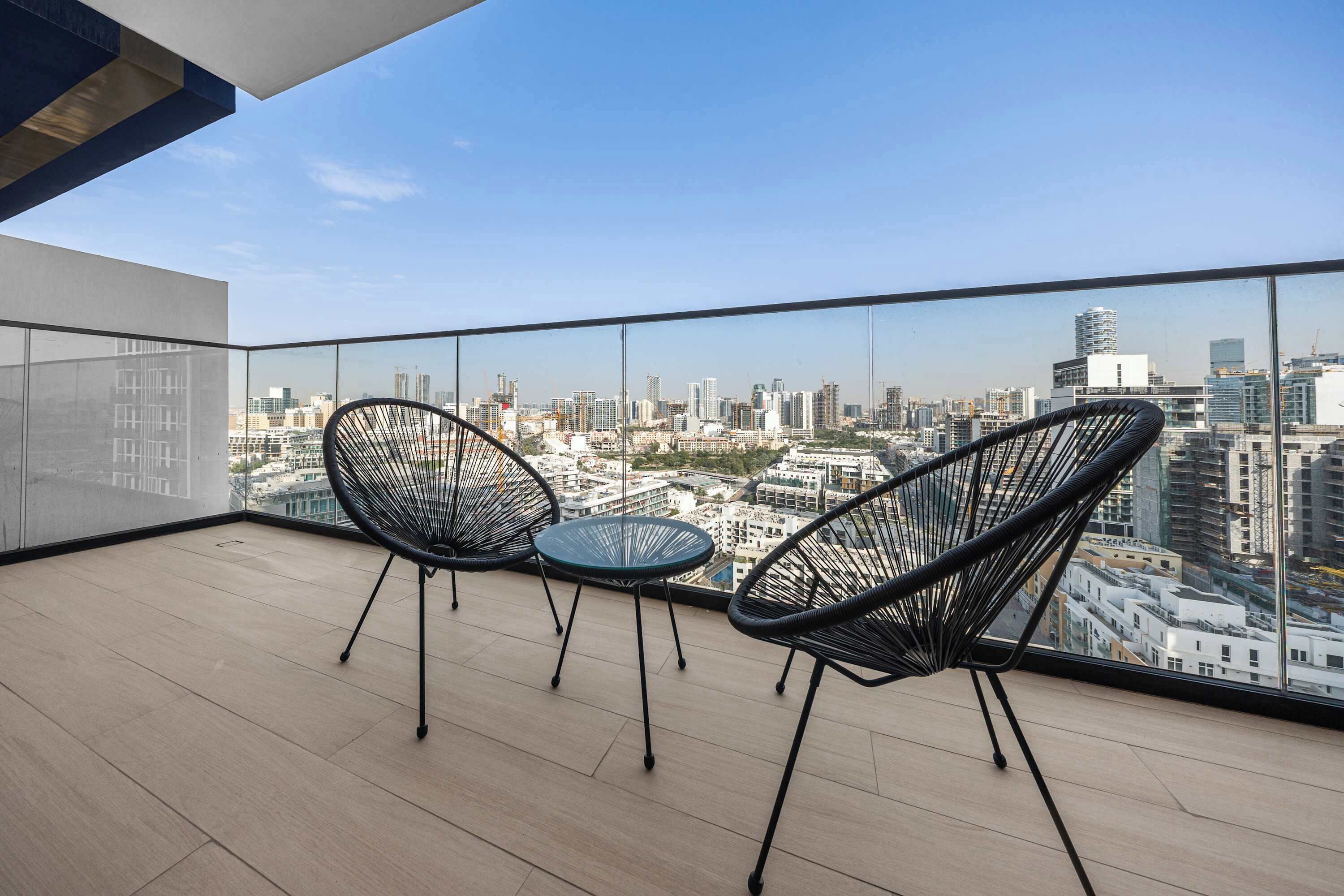 A balcony with two chairs and a table, offering a city view.