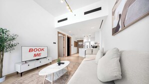 A modern living room with a sofa, a coffee table, a TV, and a plant. - StayShort - 1-bedroom in JVC sleeps 4 with Amazing Views and Large Balcony! (JVC)