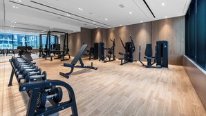 A modern gym with various exercise equipment, wooden flooring, and large windows. - StayShort - 1-bedroom in JVC sleeps 4 with Amazing Views and Large Balcony! (JVC)
