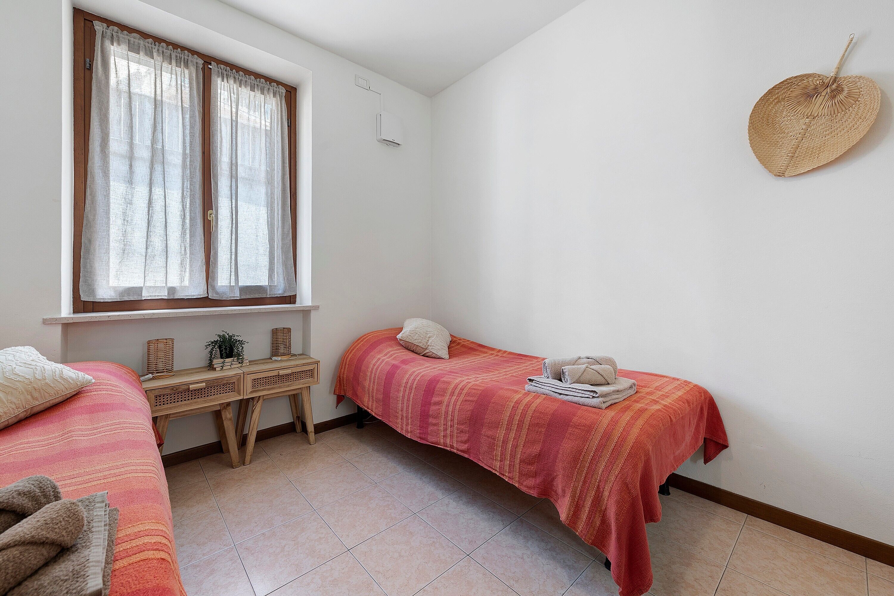 Une chambre avec deux lits, un bureau et une fenêtre avec des rideaux.