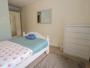Ein Schlafzimmer mit einem Bett, einem Schminktisch, einem Spiegel und Teppichboden.