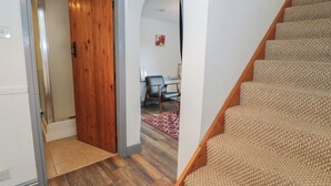 A staircase with carpeted steps, a wooden door, and a room with a desk and chair. - Ysgoldy (Dolwyddelan)