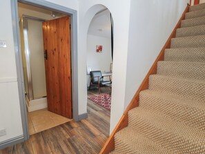 Eine Treppe mit Teppichstufen, eine Holztür und ein Raum mit Schreibtisch und Stuhl.