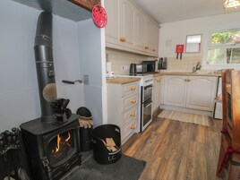 A kitchen with a wood-burning stove, white cabinets, a microwave, and a sink.
