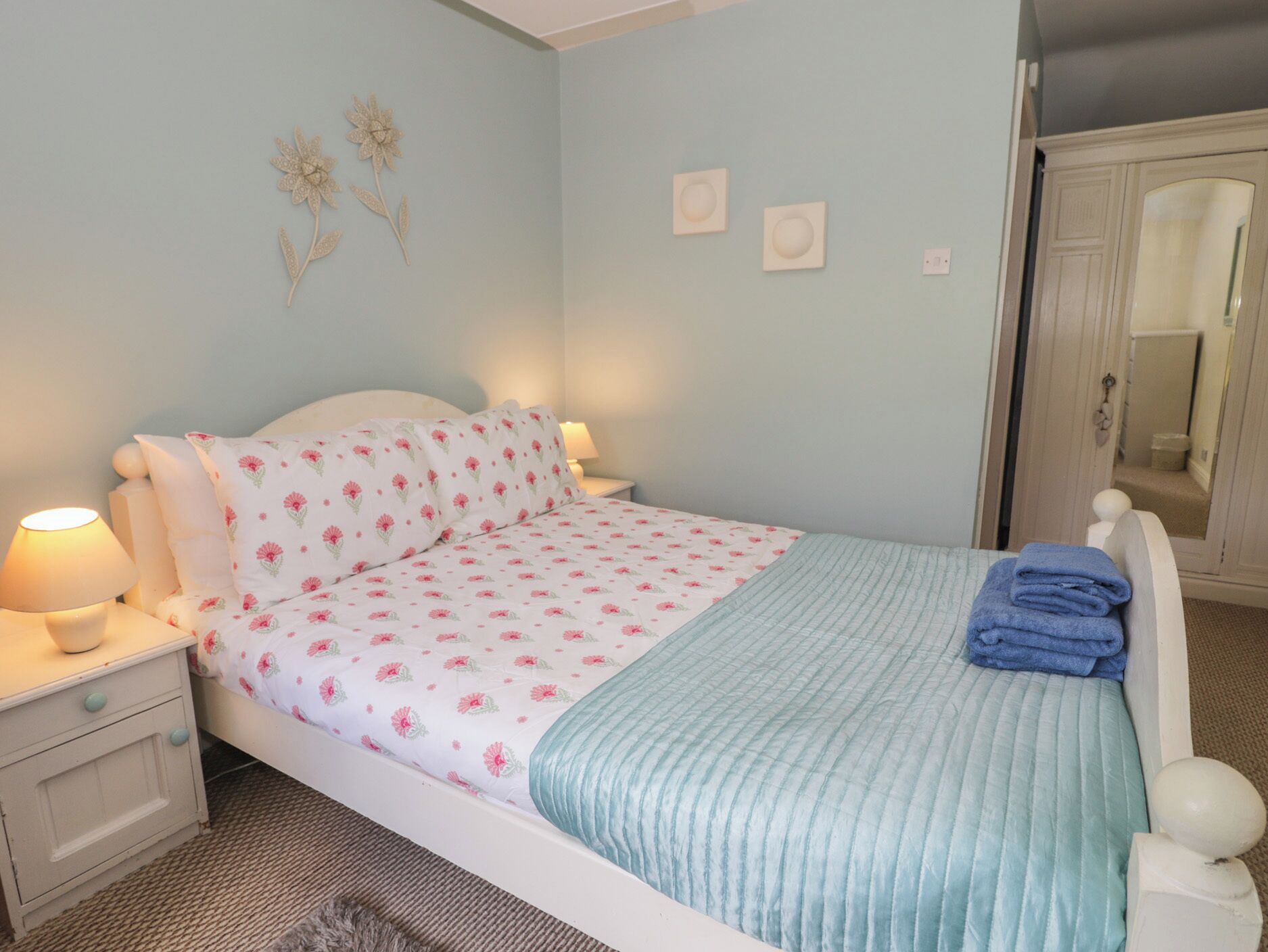 A bedroom with a bed, nightstands, a lamp, and a door.