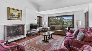 A living room with a fireplace, a sofa, a TV, and a large window with a view. - Holiday Home 'Finca Tolombreo Casa Gabriel' in Cudillero (Cudillero)