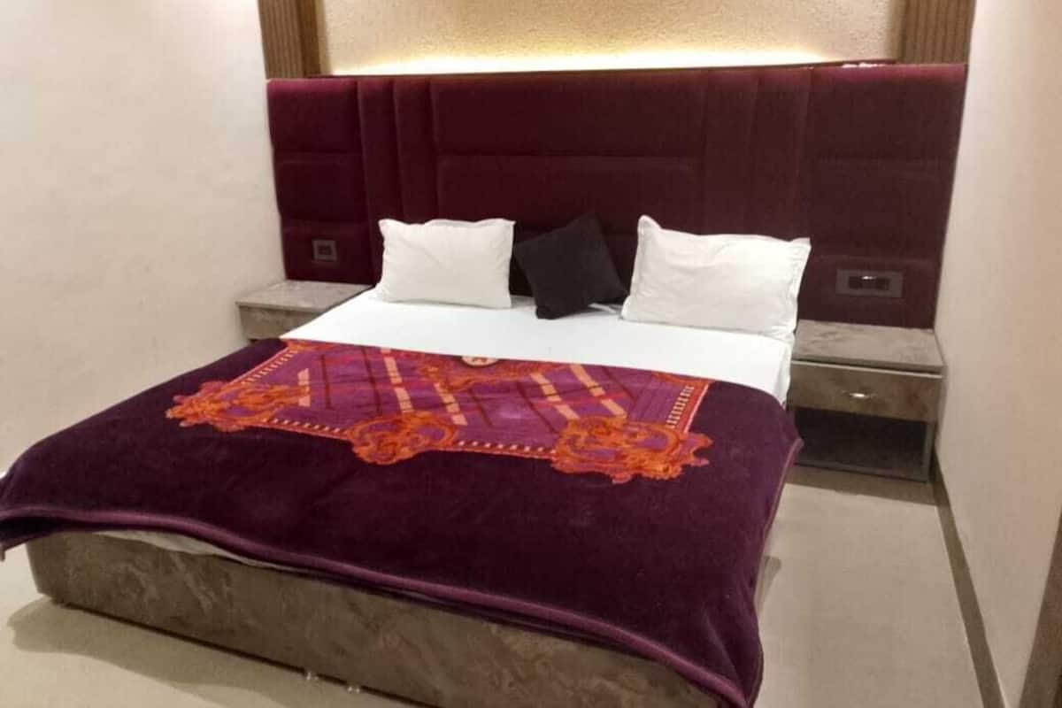 A bed with a headboard, pillows, a blanket, and a bedside table.
