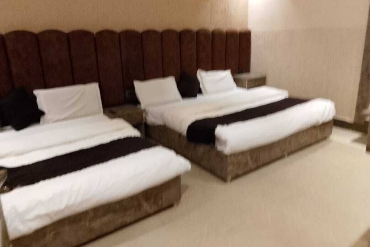 A hotel room with two beds, a headboard, and a nightstand.