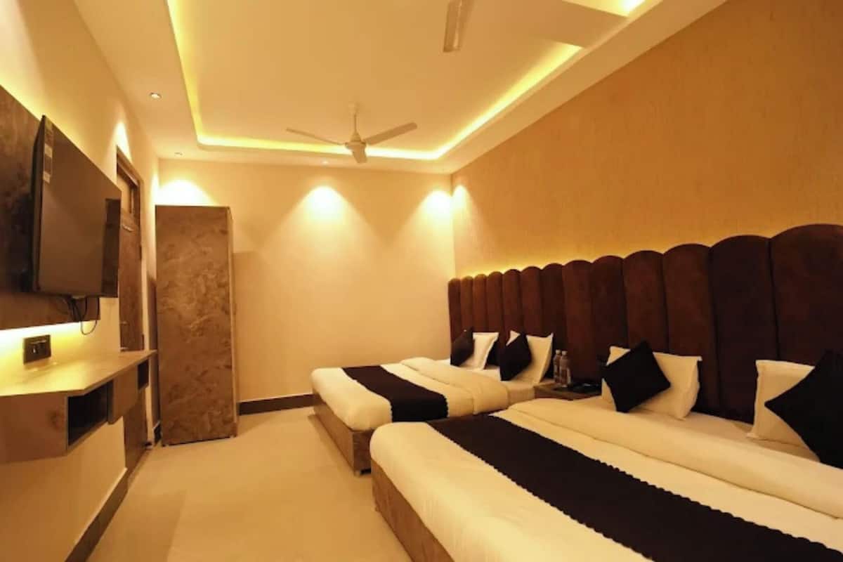 A hotel room with two beds, a television, a ceiling fan, and a minibar.