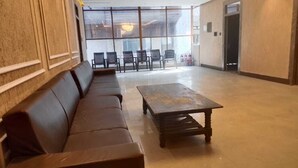 En rymlig entréhall med en lång, brun lädersoffa, ett träbord och en rad stolar placerade framför ett stort fönster med utsikt.