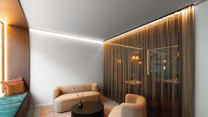 Una sala de estar moderna con sofá, sillón, mesa de centro y un jarrón decorativo.