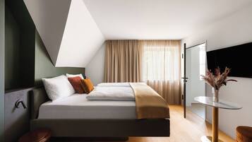 A modern bedroom with a bed, a bedside table, a mirror, and a window with curtains.