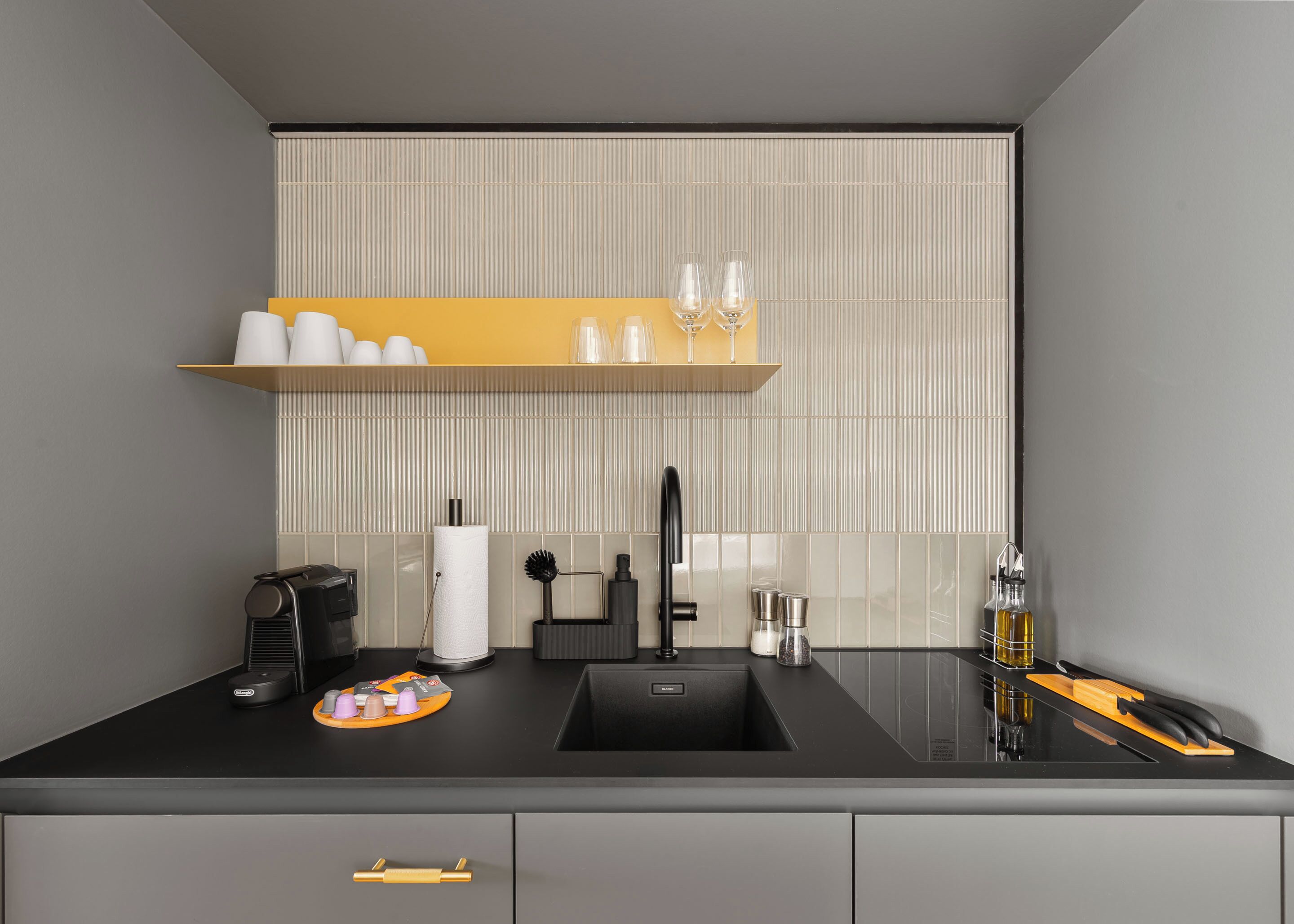 A modern kitchen with a black countertop, a sink, a coffee machine, and a knife block.