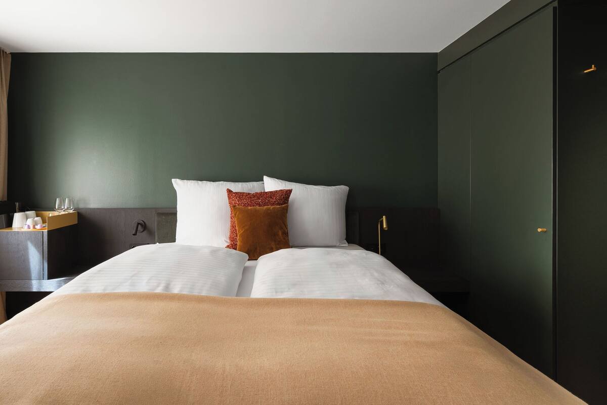 Ein Hotelzimmer mit Bett, Schreibtisch mit Lampe, Stuhl und Kleiderschrank.