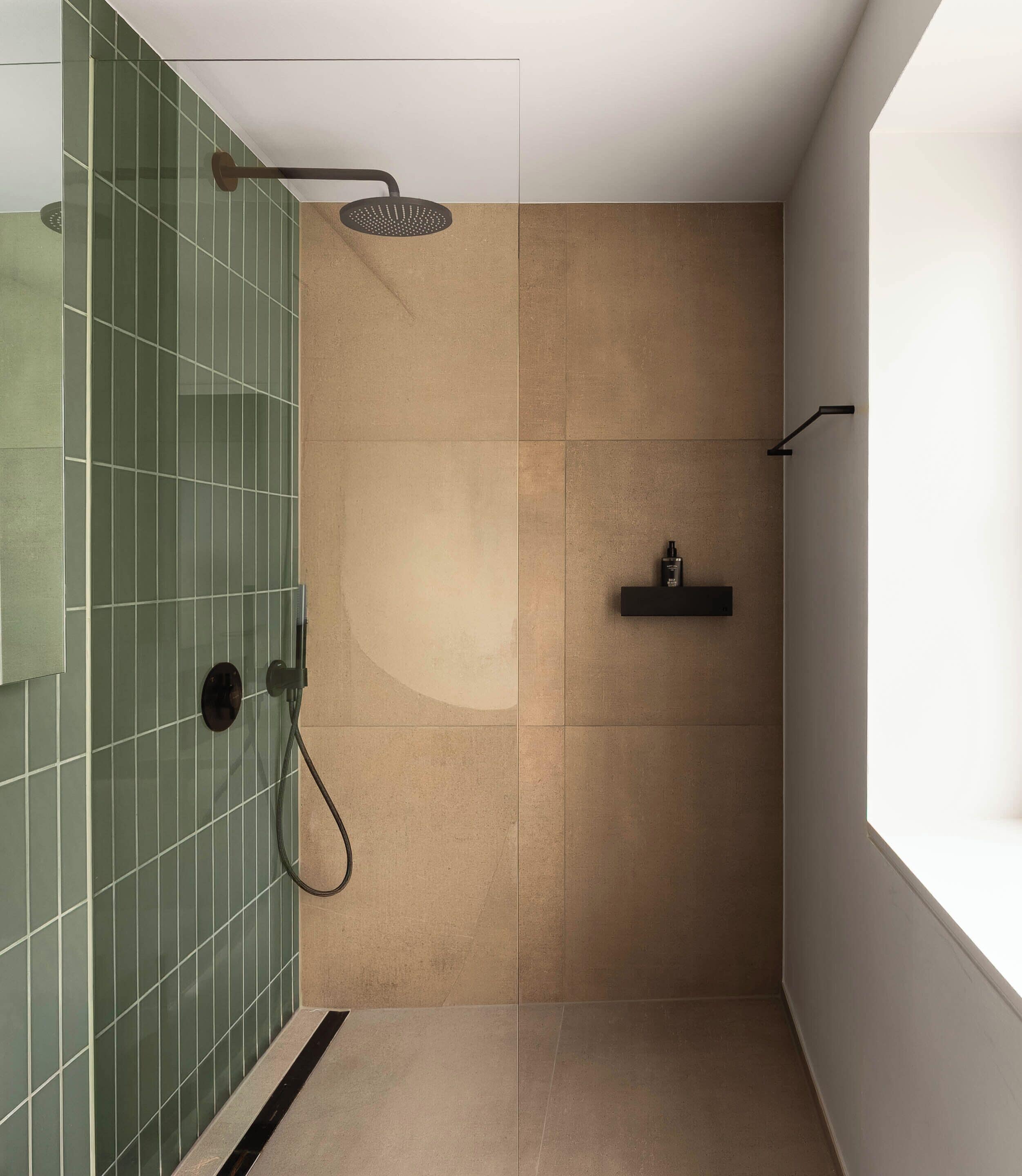 A modern shower area with a rain showerhead, a handheld showerhead, and a shelf with toiletries.
