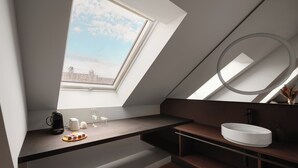 Un baño moderno con tragaluz, un lavamanos redondo y una cafetera en la encimera.