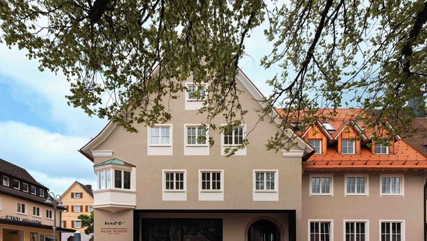 Un edificio con varias ventanas, mesas al aire libre y un letrero que dice 'WILMA WUNDER'.