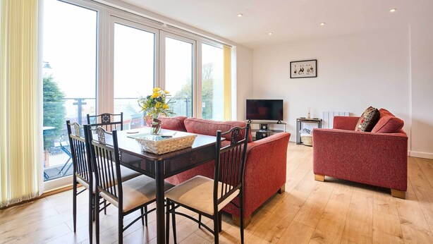 Una sala de estar con una mesa de comedor, un sofá rojo y un televisor.