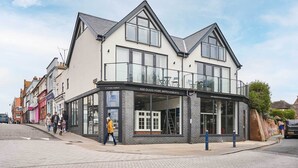Un edificio de dos pisos con grandes ventanales y un balcón, con la leyenda 'A&B Glass Home Improvements'.