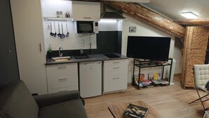 Ein gemütlicher Wohnraum mit Küchenzeile, Flachbildfernseher und Bücherregal.