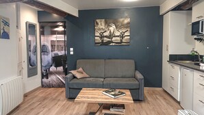 Ein Wohnzimmer mit einem grauen Sofa, einem Holztisch und einem Bild einer Motorrad an der Wand.