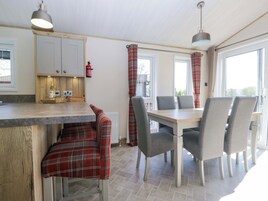 Una cocina moderna con zona de comedor, armarios de madera y un banco de cuadros rojos.