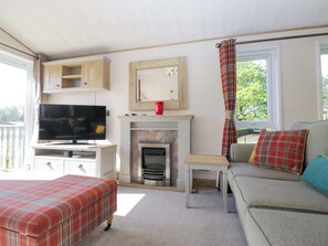 A living room with a television, fireplace, sofa, and ottoman. - Borwick Heights 17 (Carnforth)