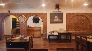 A restaurant with brick walls, wooden furniture, a Buddha head sculpture, and a tiger painting.