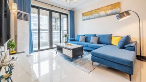 Un saló modern amb un sofà blau, una taula de centre, un llumí i un quadre a la paret.