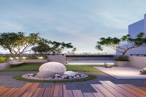 Eine Terrassengarten mit Sitzgelegenheit im Kreis, Stein-Pflanzgefäßen und Blick auf die Skyline der Stadt.