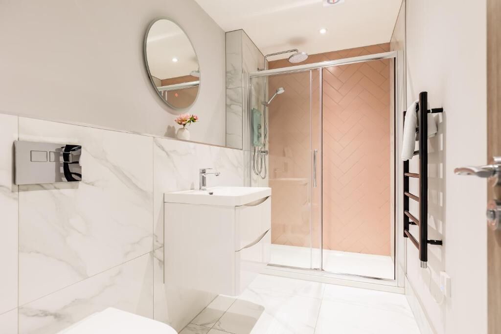 A modern bathroom with a glass shower enclosure, a marble vanity, and a wall-mounted towel rack.