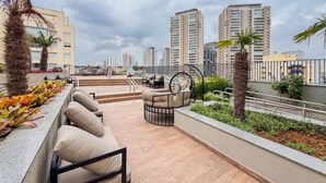 Terraza en la azotea con mobiliario exterior, piscina y vistas de la ciudad.
