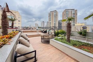 Une terrasse sur le toit avec des sièges extérieurs, une piscine et une vue sur la ville.