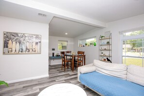 A modern living room with a sofa, a dining table with chairs, a kitchen area, and a large window. - The De Luna - Pensacola FL (Pensacola)