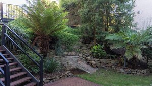A garden with a stone wall, a wooden staircase, and various plants. - Mountain view house (Trevallyn)