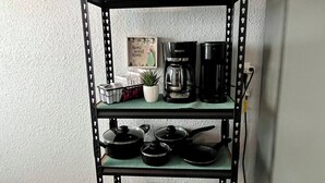 A kitchen shelf with cookware, a coffee maker, and a potted plant. - 2BDR+Extd Stay Discounts+Central+RemoteWork (Corpus Christi)