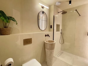 A modern bathroom with a glass shower enclosure, a large mirror, a potted plant, and a toilet. - Fulham Design-led 2BR Apartment Near Olympia | Family Friendly | Sleeps 6 (London)