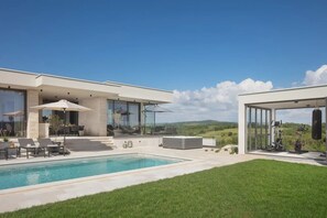 Ein modernes Haus mit Schwimmbad, Sitzgelegenheiten im Freien und Fitnessgeräten.