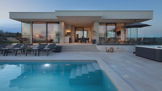 Ein modernes Haus mit Pool, Sitzgelegenheit im Freien und Blick auf die Landschaft.